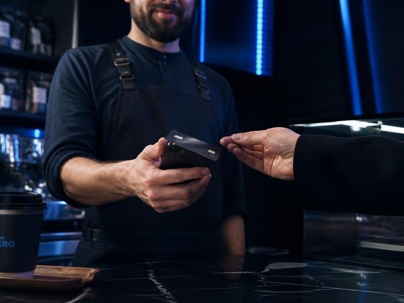 Cafe staff member taking a contactless card payment on a phone